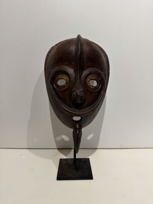 an image of a wooden mask on a stand on a white surface