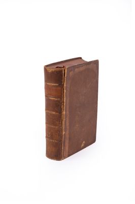 an old brown book sitting on top of a white surface