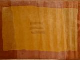 an orange and yellow rug on a wooden floor with a brick wall in the background
