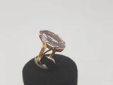 un gros plan d'une bague posée sur un socle noir, sur une surface blanche