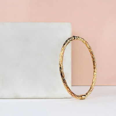 a gold bang bracelet sitting on top of a marble block
