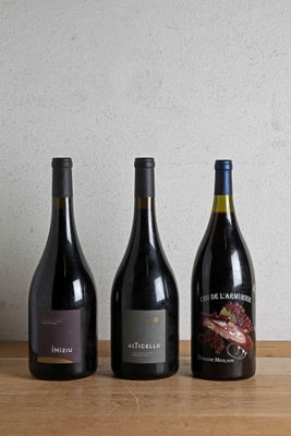 three bottles of wine are lined up on a wooden table