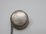 an antique silver pocket watch with a chain on a white surface