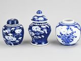 trois vases bleus et blancs ornés de fleurs, posés sur une table