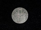 a silver coin with a cross on it on a black surface