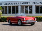 an old red convertible car parked in front of a building