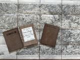 deux vieux livres posés sur une carte, elle-même posée sur une table