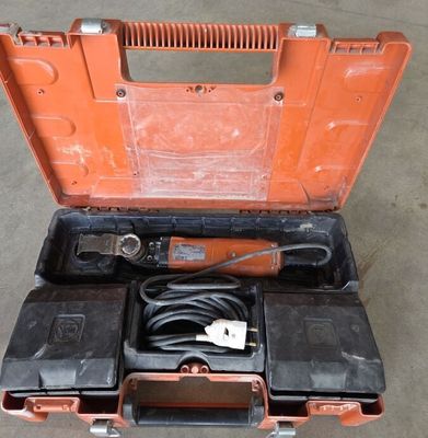 une boîte à outils orange contenant des outils, posée sur un sol en béton