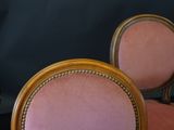 a pink chair with a gold frame and a black background