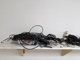 a pile of wires and cords on a white shelf