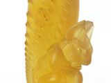 a yellow glass figurine of a squirrel on a white background