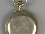 an old silver pocket watch sitting on top of a white table