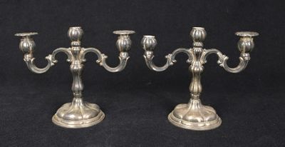 a pair of silver plated candlesticks on a black background