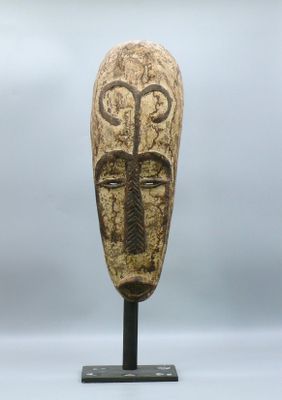 gros plan d'un masque en bois sur un support métallique