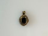 a picture of a gold and black pendant on a white surface