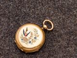 une petite montre de poche en or ornée d'un oiseau