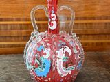 a red vase sitting on top of a wooden table