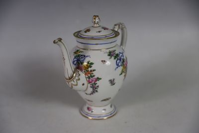une théière blanche décorée de fleurs, posée sur une table