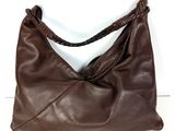 sac à main en cuir marron avec des anses tressées sur un fond blanc