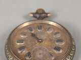 une montre de poche en or posée sur une table, sur fond blanc