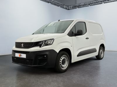 La camionnette blanche est garée dans une grande pièce au sol gris.