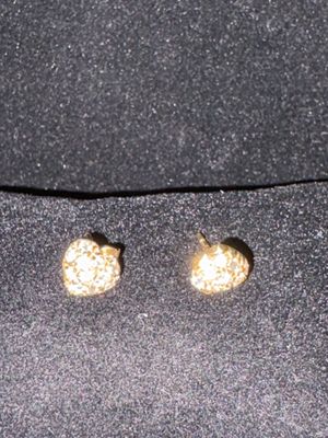 two pairs of gold colored stud earrings on a black cloth