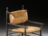 une vieille chaise en bois avec une assise tressée posée sur une surface grise