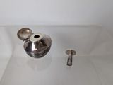 a silver vase and two silver spoons on a white surface