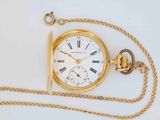 a gold pocket watch with a chain on a white surface