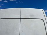 a white van parked in a parking lot with a blue sky in the background