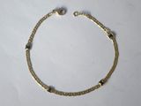 gros plan d'un bracelet en or sur une surface blanche