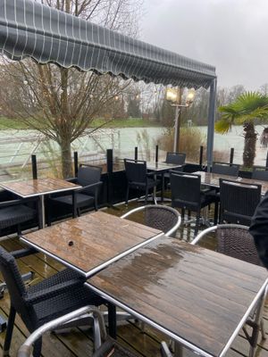 des tables et des chaises sur une terrasse en bois donnant sur un plan d'eau