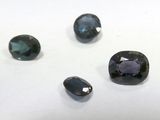four different colored gems are arranged on a white surface