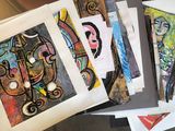 a lot of paintings on a table with papers on it