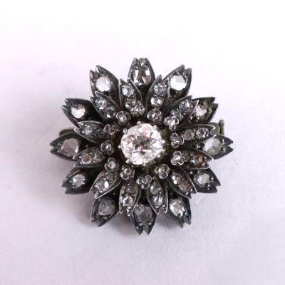 a close up of a diamond flower broochle on a white surface