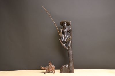 statue représentant un homme assis sur un arbre, accompagné d'un chien et d'un poisson