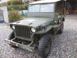 une jeep verte garée sur un parking en gravier