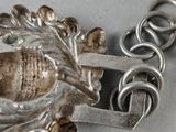 a silver necklace that has a bird on it