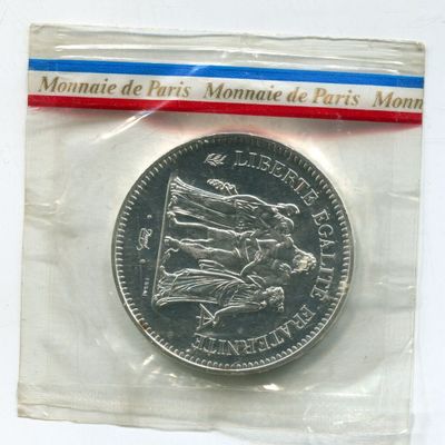 a silver coin in a plastic bag on a white surface