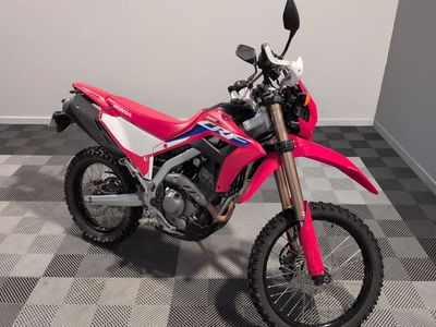 une photo d'une moto tout-terrain rose garée sur un sol à damier