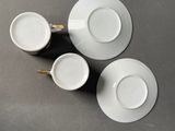 three white cups and saucers sitting on top of a table