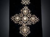 a close up of a cross with pearls on it on a black surface