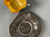an antique silver plate with a yellow bowl on top of it