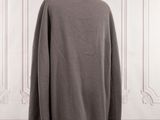 the back of a coat on a mannequin stand in front of a white wall