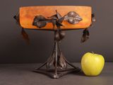 an apple sitting next to a lamp with leaves on it