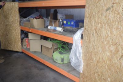 un homme debout à côté d'une étagère remplie de cartons et encore de cartons