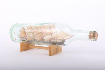 un petit navire dans une bouteille en verre sur un support en bois