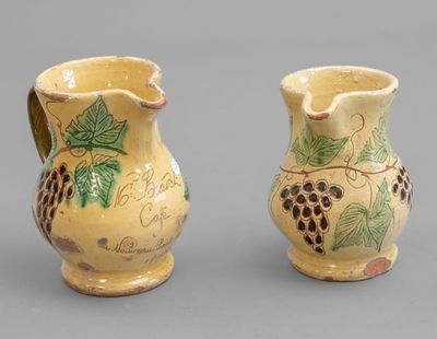 pair of ceramic vases with grapes painted on them on a gray surface