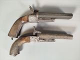 two old guns are sitting on a white surface next to each other