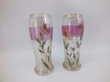 two vases with flowers painted on them sitting on a table